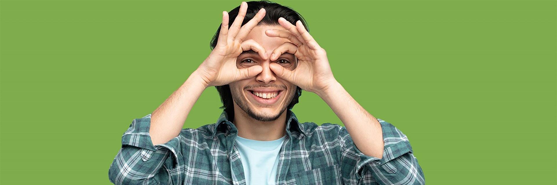 Bild zeigt einen jungen Mann der eine Brille mit seinen Findern formt