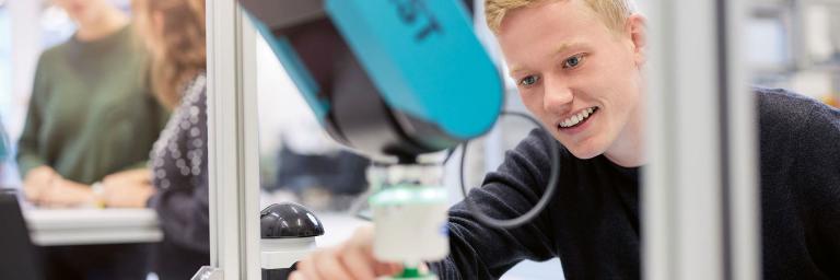 Bild zeigt jungen Mann an einem Roboterarm beim IWT